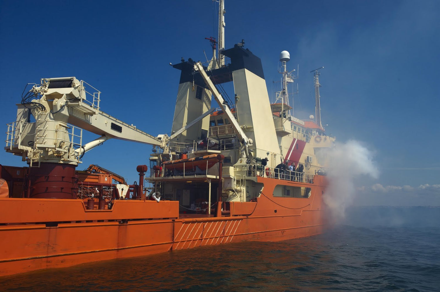 301 Trainer smoke machine simulating onboard fire during marine safety training exercise on an orange vessel.
