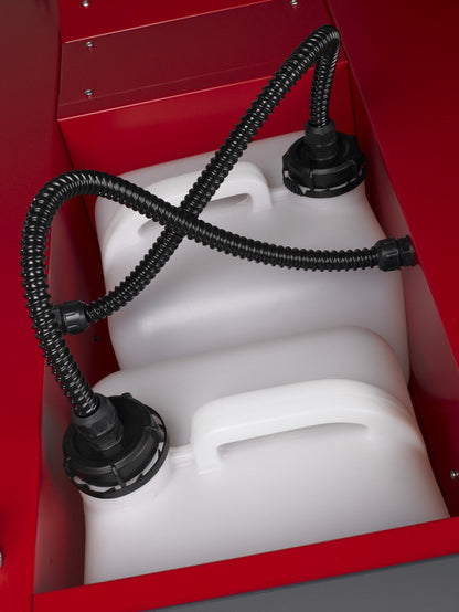Close-up of two white fluid tanks with black caps and connected hoses inside the MSS Trainer X-Stream smoke machine.