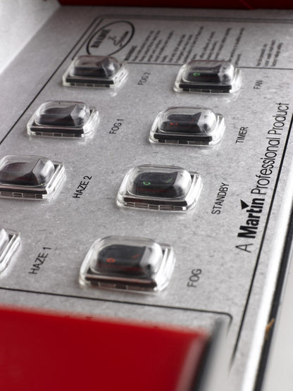 Close-up of control panel switches on the MSS Trainer X-Stream smoke machine, showing labeled buttons for fog, haze, timer, and fan functions.